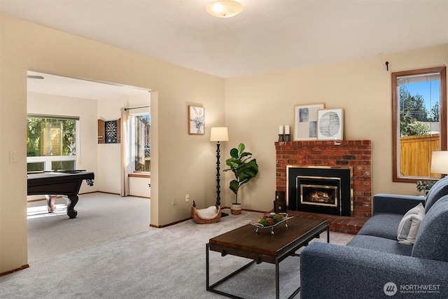 living room with light colored carpet, a healthy amount of sunlight, pool table, and a brick fireplace