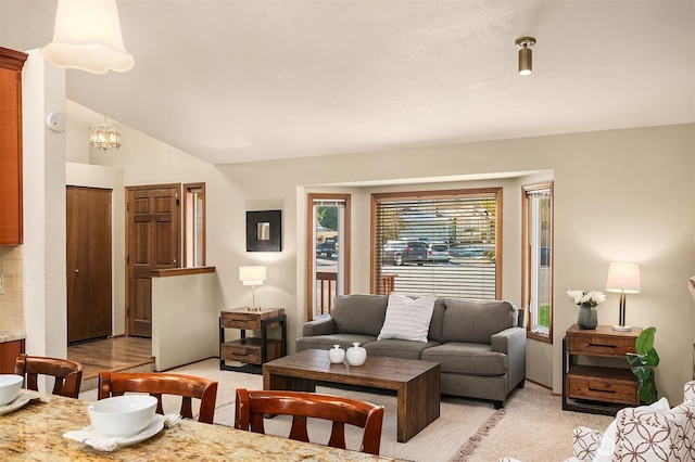 living room featuring lofted ceiling, light colored carpet, and a notable chandelier