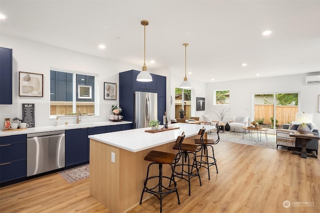 kitchen with blue cabinets, a breakfast bar, a center island, pendant lighting, and stainless steel appliances