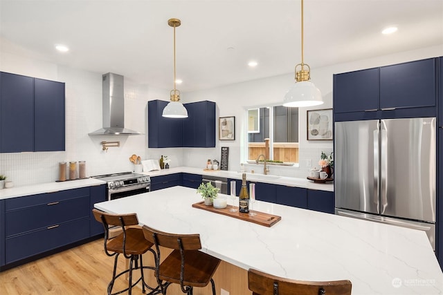 kitchen with appliances with stainless steel finishes, blue cabinetry, and wall chimney range hood