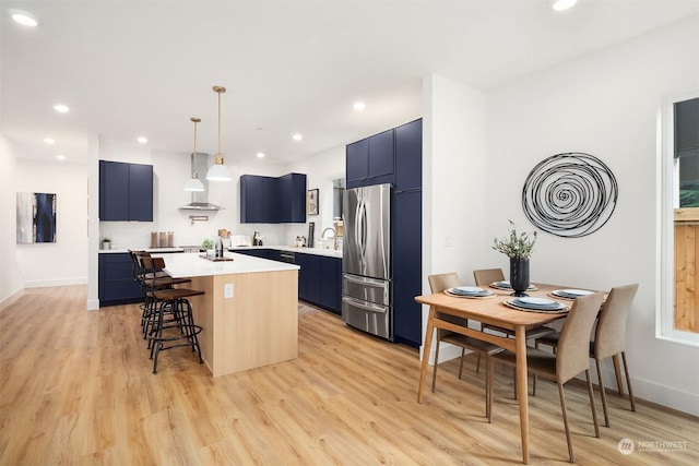 kitchen featuring pendant lighting, blue cabinetry, stainless steel refrigerator, a kitchen island, and a kitchen bar