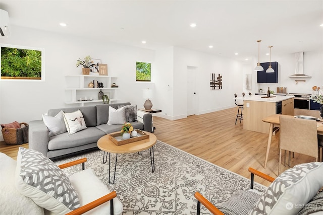 living room with a wall mounted air conditioner and light hardwood / wood-style floors