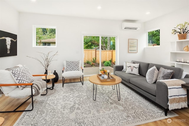 living room with plenty of natural light, light wood-type flooring, and a wall unit AC