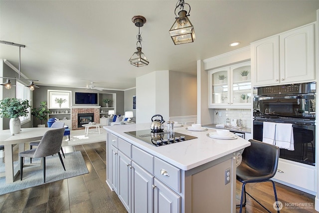 kitchen featuring white cabinetry, a center island, pendant lighting, and black appliances