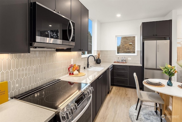 kitchen featuring stainless steel appliances, sink, light hardwood / wood-style floors, and decorative backsplash