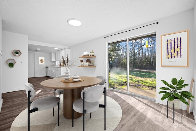 dining space featuring hardwood / wood-style floors, sink, and a textured ceiling