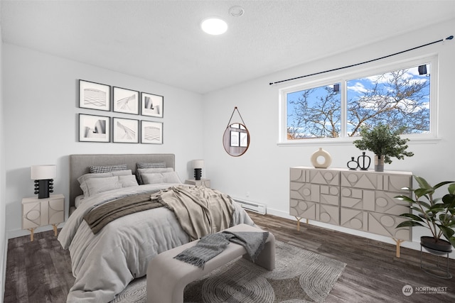 bedroom with a textured ceiling, baseboard heating, wood finished floors, and baseboards