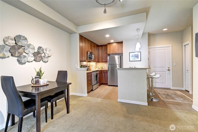 kitchen featuring recessed lighting, appliances with stainless steel finishes, light countertops, baseboards, and light colored carpet