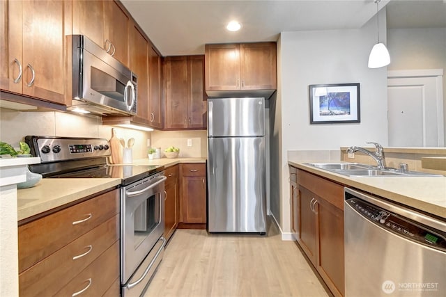 kitchen with a sink, brown cabinetry, and stainless steel appliances