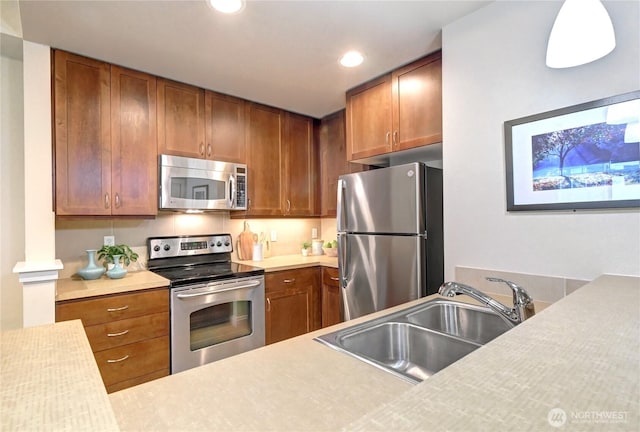 kitchen featuring a sink, stainless steel appliances, brown cabinetry, and light countertops