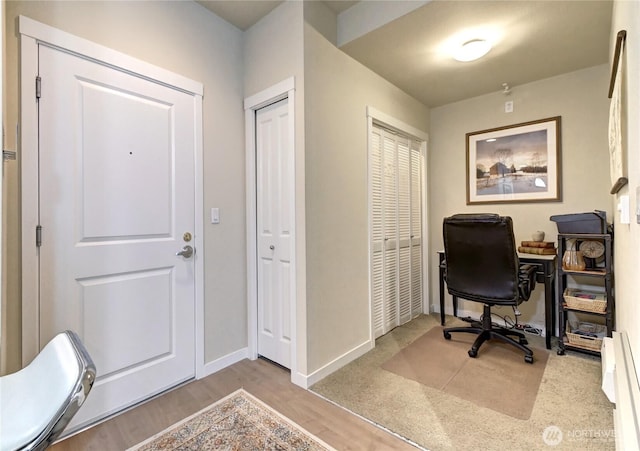 office space featuring wood finished floors, baseboards, and a baseboard radiator