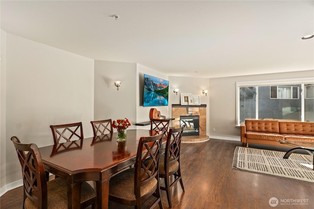 dining space with dark wood-type flooring and a tile fireplace