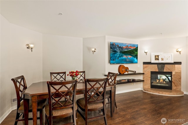 dining space with hardwood / wood-style flooring and a premium fireplace