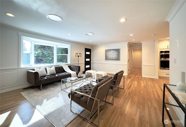 living area with crown molding, recessed lighting, light wood-type flooring, and a decorative wall