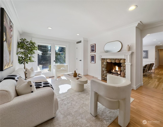 living area featuring a fireplace, crown molding, recessed lighting, visible vents, and light wood-type flooring