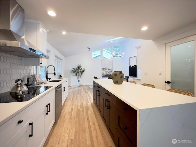 kitchen featuring lofted ceiling, a kitchen island, a sink, wall chimney range hood, and dishwasher