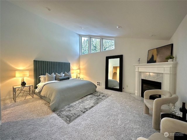 carpeted bedroom featuring a premium fireplace, visible vents, and baseboards