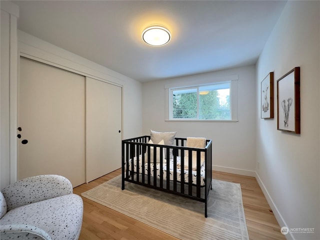 bedroom featuring a closet, light wood-style flooring, and baseboards