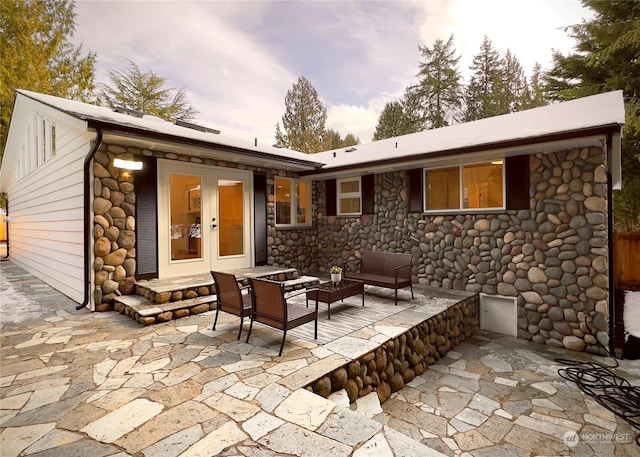 back of property featuring stone siding, french doors, a patio area, and outdoor lounge area