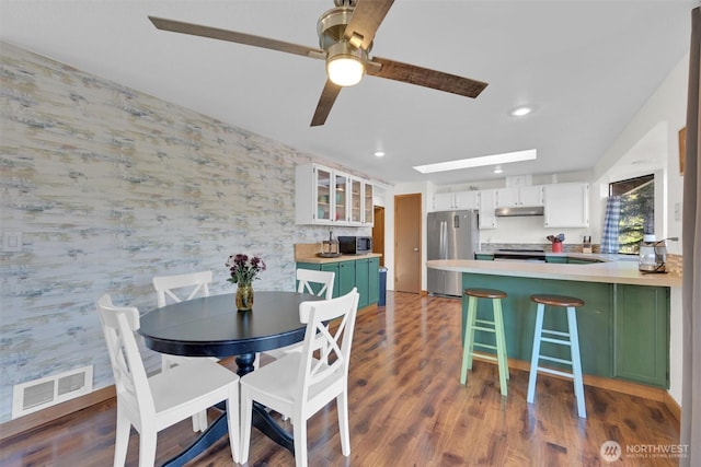 dining area with dark hardwood / wood-style flooring, a skylight, and ceiling fan