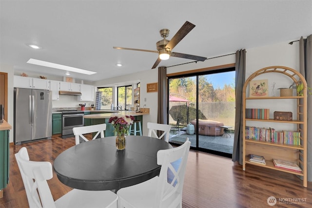 dining room featuring ceiling fan, a skylight, and wood-type flooring