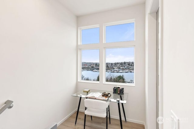 office featuring light hardwood / wood-style flooring and a water view