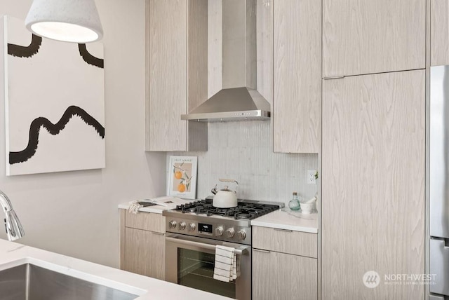 kitchen featuring appliances with stainless steel finishes, tasteful backsplash, sink, light brown cabinets, and wall chimney exhaust hood