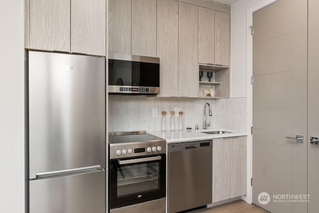 kitchen with backsplash, appliances with stainless steel finishes, sink, and light brown cabinets