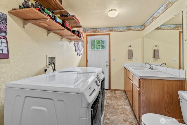 laundry area with a textured ceiling, laundry area, a sink, baseboards, and independent washer and dryer