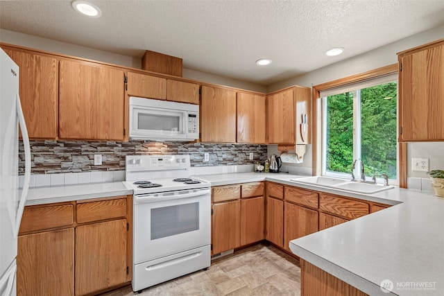 kitchen featuring recessed lighting, white appliances, a sink, light countertops, and decorative backsplash