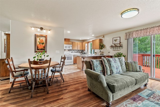 living room featuring a textured ceiling, recessed lighting, and light wood-style floors