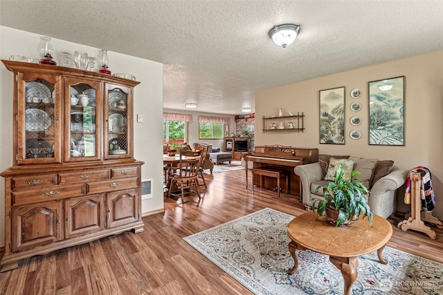 living room featuring light wood-style floors, visible vents, and a textured ceiling