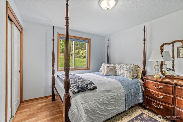 bedroom featuring light wood-style floors, a closet, a textured ceiling, and baseboards