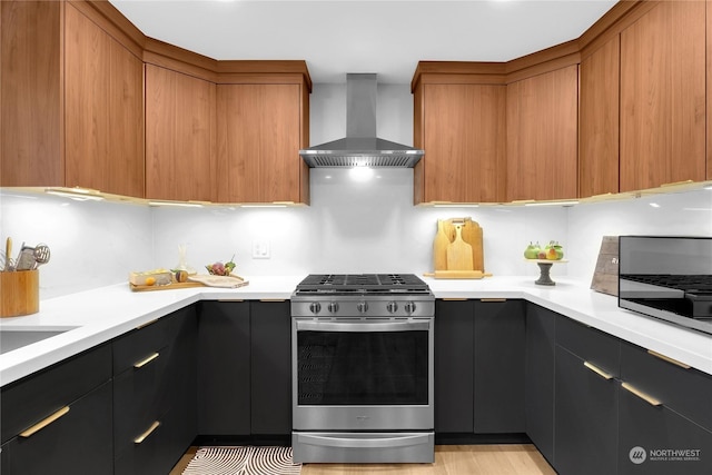 kitchen with stainless steel gas stove, wall chimney range hood, and sink