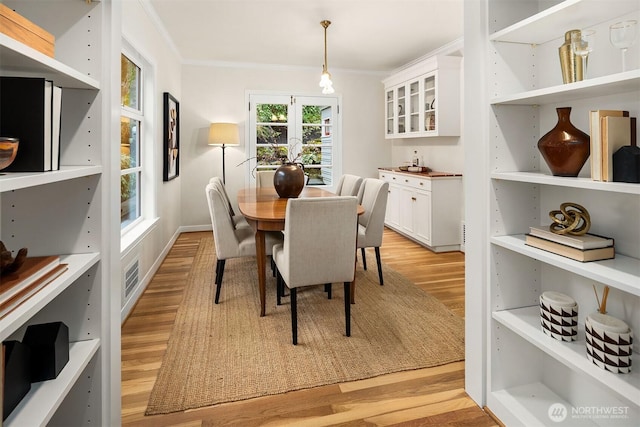 dining area featuring light wood-style floors, visible vents, and ornamental molding