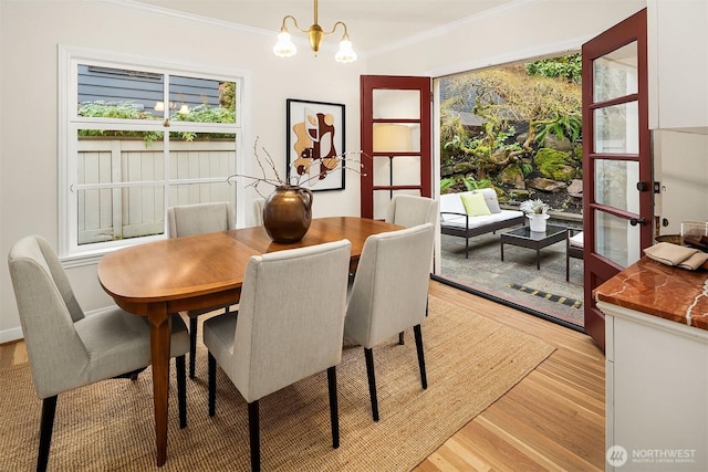 dining room featuring a chandelier, light wood-type flooring, and crown molding