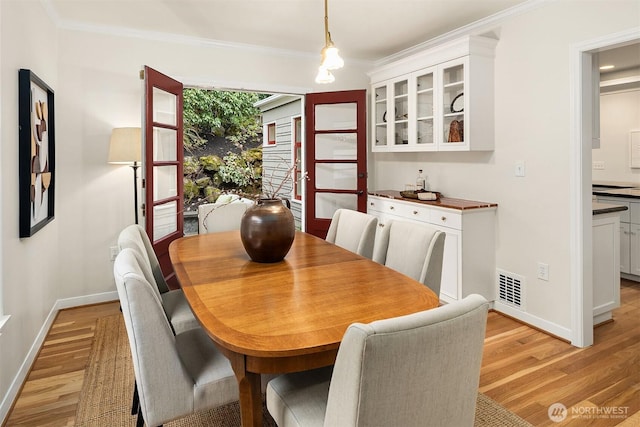 dining area featuring ornamental molding, visible vents, and light wood-style floors