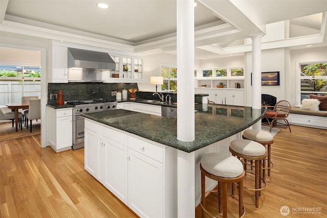 kitchen with wall chimney range hood, appliances with stainless steel finishes, and white cabinetry