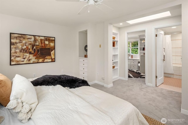 bedroom with a skylight, recessed lighting, light colored carpet, ensuite bath, and baseboards