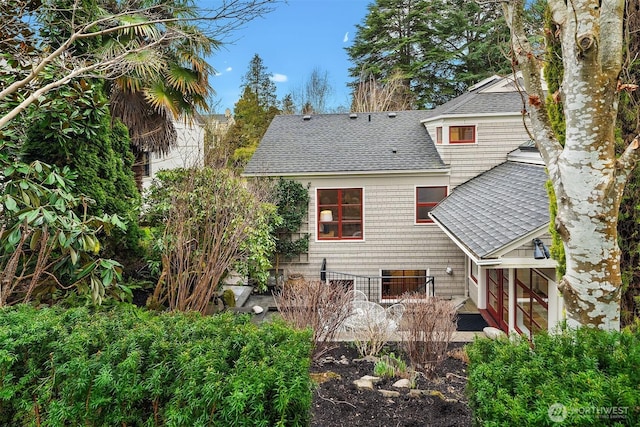 rear view of property featuring roof with shingles and a patio