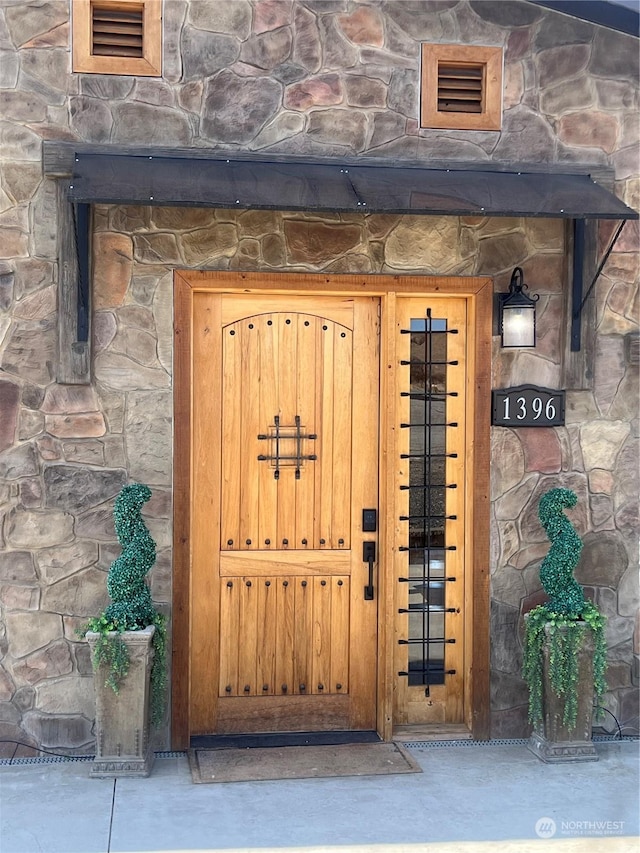 property entrance with stone siding and visible vents