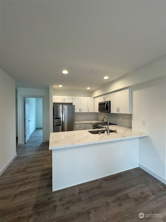 kitchen with sink, white cabinets, dark hardwood / wood-style flooring, kitchen peninsula, and stainless steel appliances