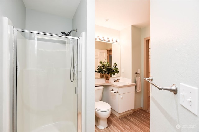 bathroom with vanity, hardwood / wood-style flooring, a shower with door, and toilet