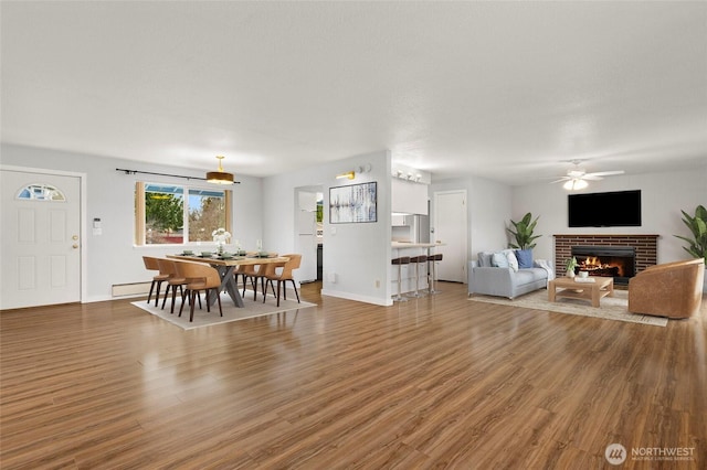 living room featuring ceiling fan, hardwood / wood-style floors, a fireplace, and a baseboard radiator