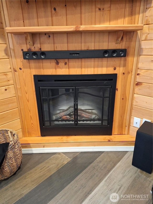 interior details featuring wood finished floors and a glass covered fireplace