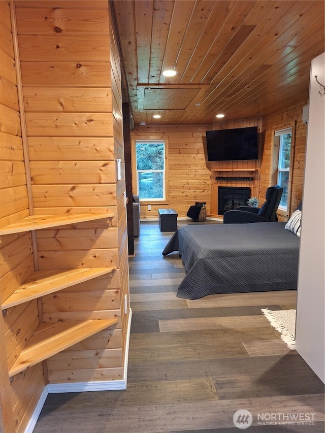 bedroom featuring a fireplace, dark wood finished floors, wood ceiling, and wooden walls