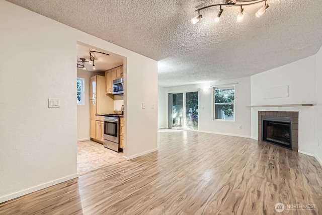 unfurnished living room with a tiled fireplace, light hardwood / wood-style floors, and a textured ceiling