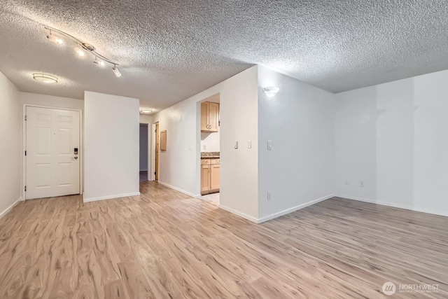 unfurnished room with a textured ceiling and light wood-type flooring