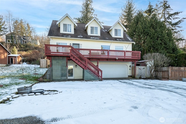 snow covered back of property with a wooden deck and a garage