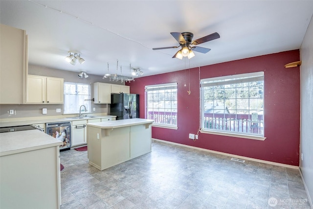 kitchen with sink, ceiling fan, dishwasher, a kitchen island, and black fridge